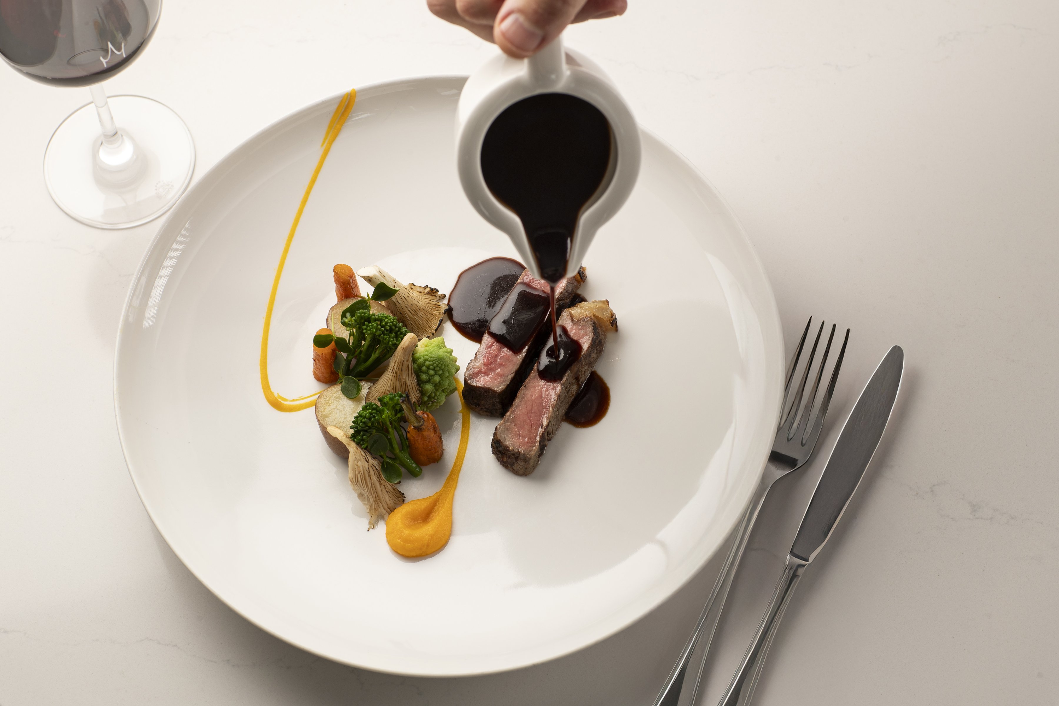 Ein saftiges Steak mit Soße, serviert mit einem Glas Rotwein.
