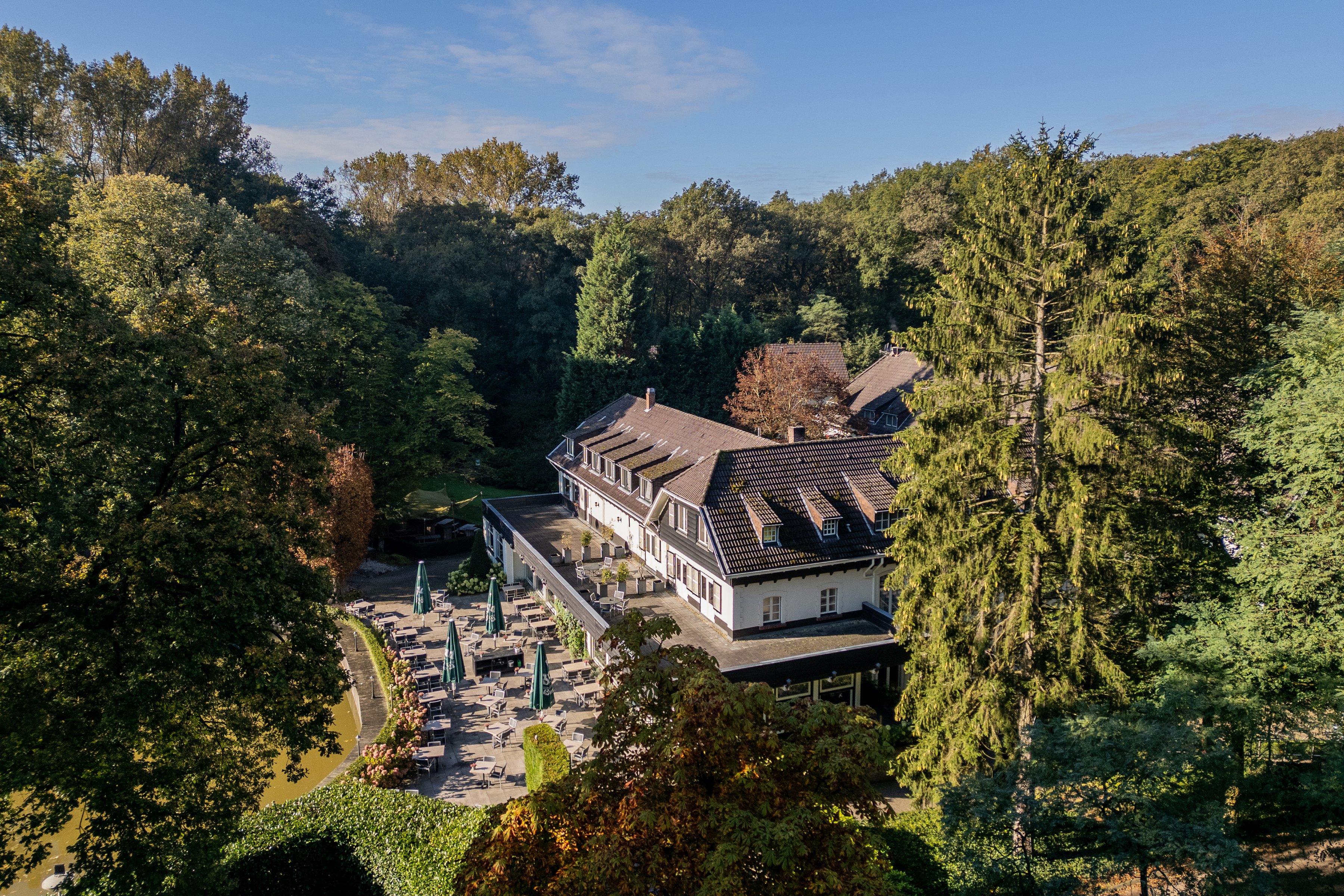 Luchtfoto van Hotel De Bovenste Molen, omringd door het groene bosgebied van Jammerdal.